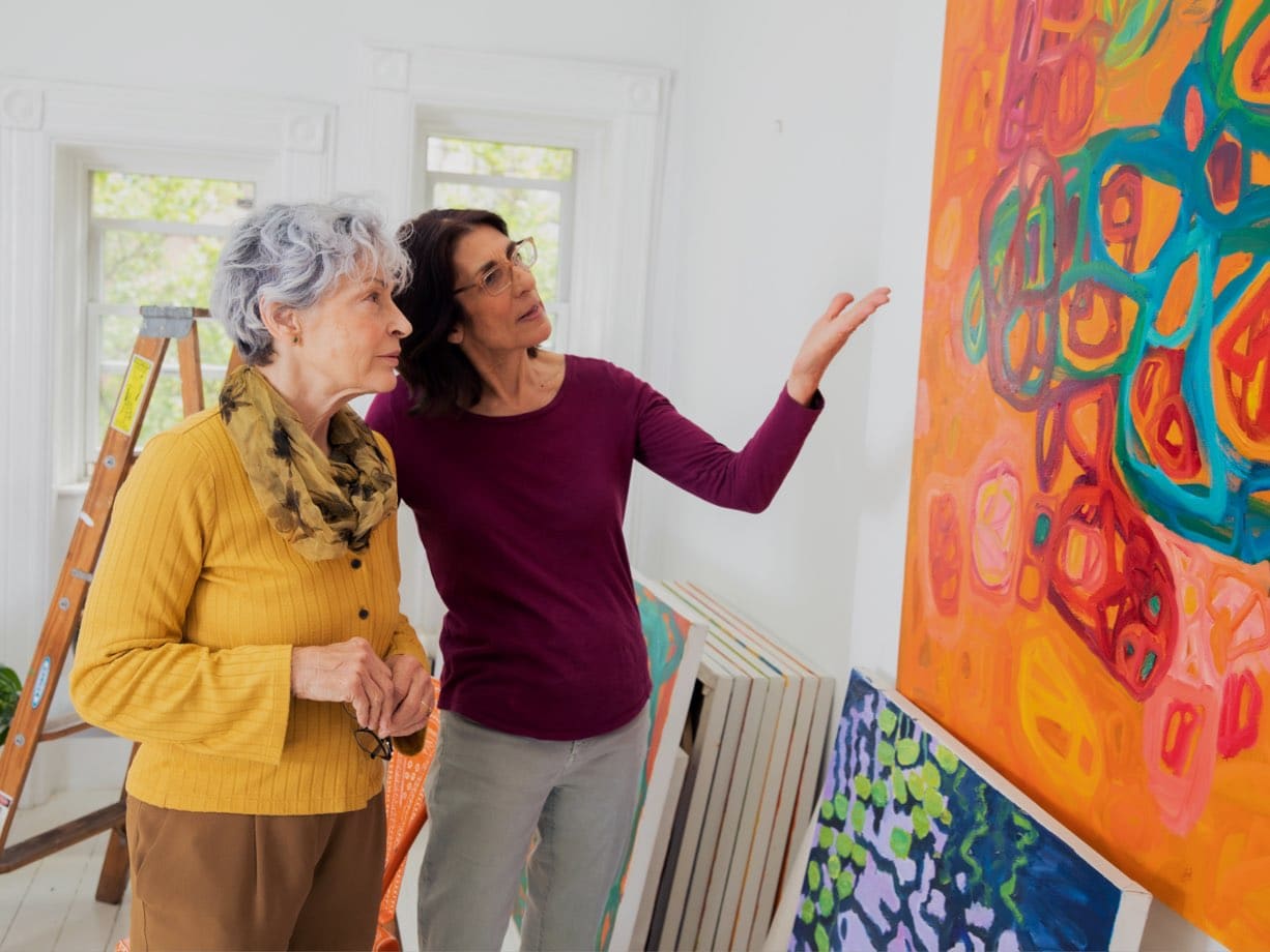 Elderly woman and caregiver looking at a painting in New York City